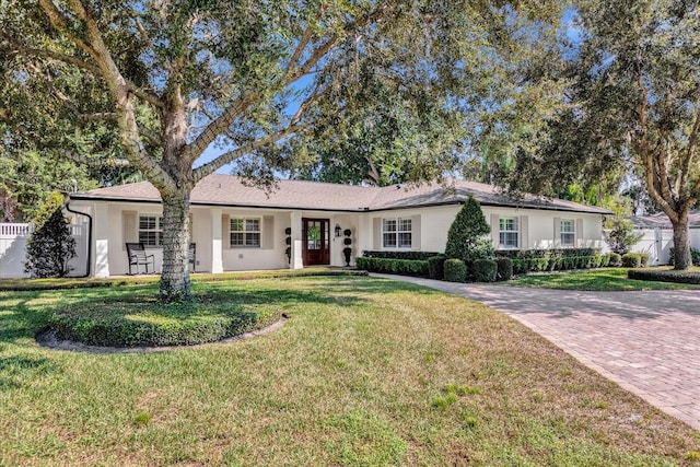 ranch-style house featuring stucco siding, a front yard, and fence