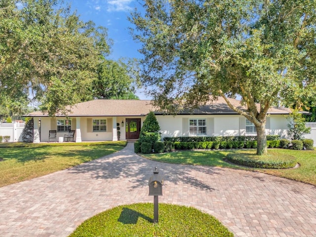 ranch-style house featuring stucco siding, a porch, a front lawn, and fence