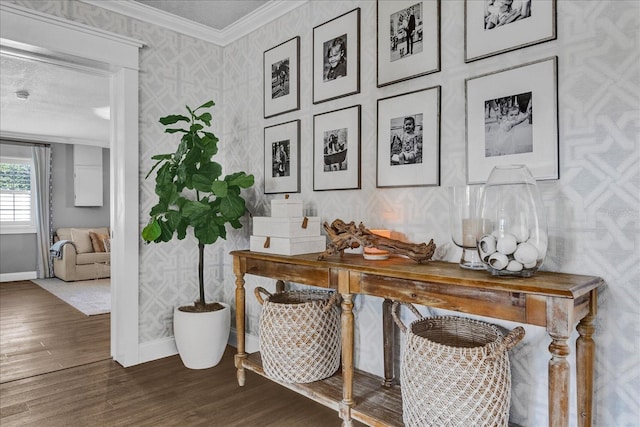 interior space featuring wallpapered walls, crown molding, baseboards, and wood finished floors