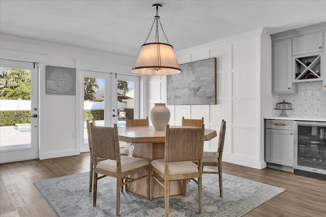 dining room with a bar, dark wood-type flooring, wine cooler, a textured ceiling, and crown molding