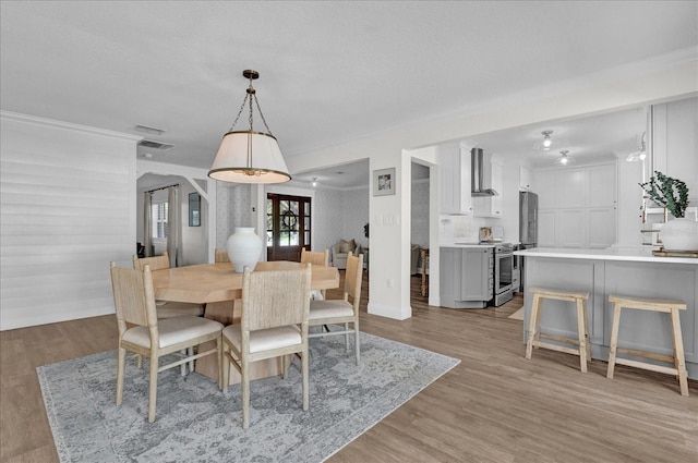 dining room with visible vents, crown molding, and light wood-type flooring