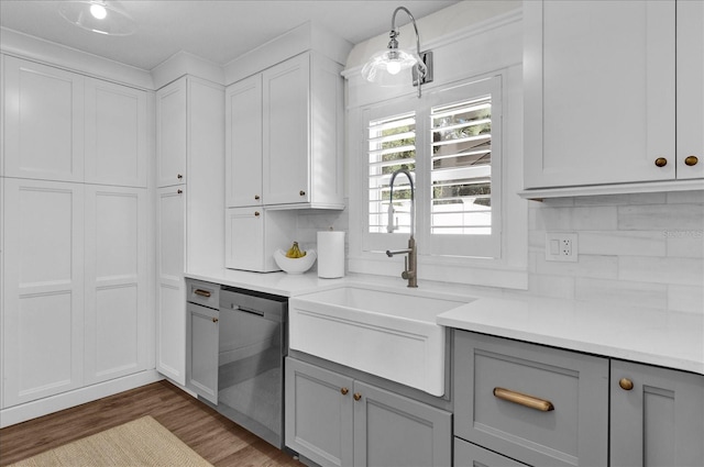 kitchen with gray cabinets, a sink, light countertops, dishwasher, and tasteful backsplash