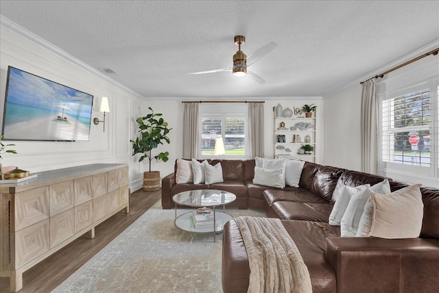 living room with visible vents, a textured ceiling, wood finished floors, and crown molding