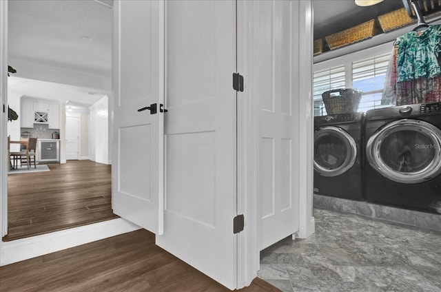 washroom with wood finished floors, washing machine and dryer, laundry area, and ornamental molding