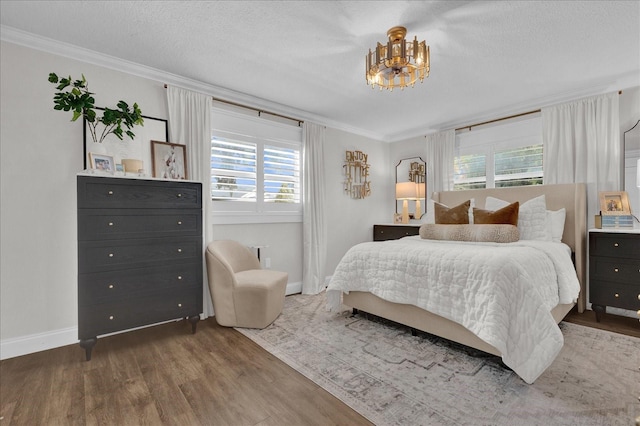 bedroom featuring ornamental molding, a textured ceiling, baseboards, and wood finished floors