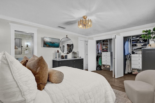 bedroom with visible vents, two closets, ornamental molding, wood finished floors, and a textured ceiling