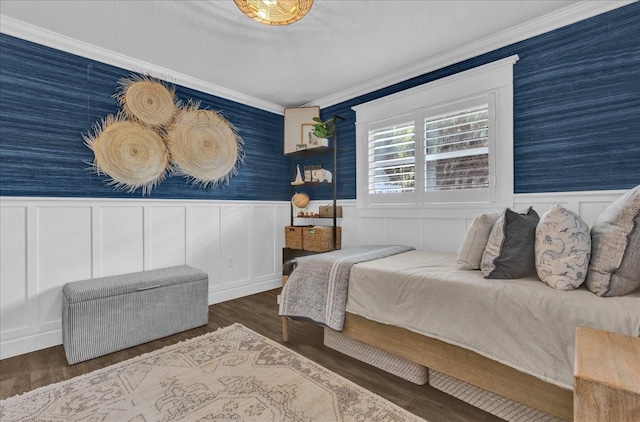 bedroom featuring wainscoting, wallpapered walls, crown molding, and wood finished floors