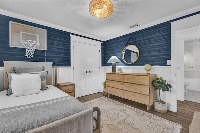 bedroom with visible vents, a wainscoted wall, and wallpapered walls