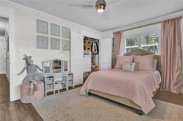 bedroom featuring a closet, a ceiling fan, wood finished floors, and crown molding