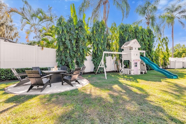 view of yard featuring a patio, a playground, a fenced backyard, and a fire pit