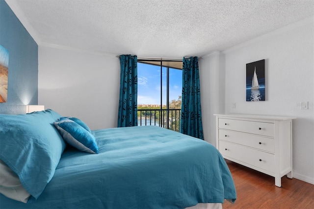 bedroom featuring a wall of windows, access to outside, wood finished floors, and a textured ceiling