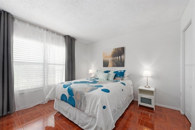 bedroom featuring tile patterned flooring, a textured ceiling, and baseboards