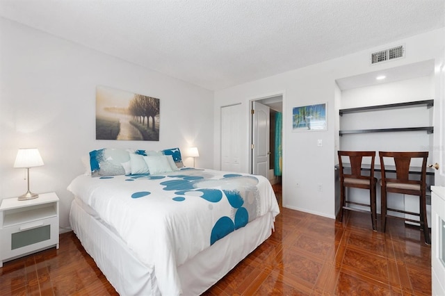 bedroom featuring visible vents, a textured ceiling, and baseboards