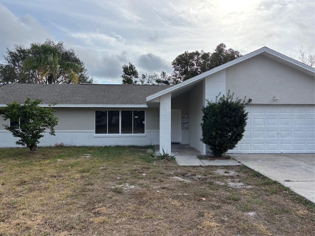 ranch-style house featuring a garage, brick siding, concrete driveway, roof with shingles, and a front yard