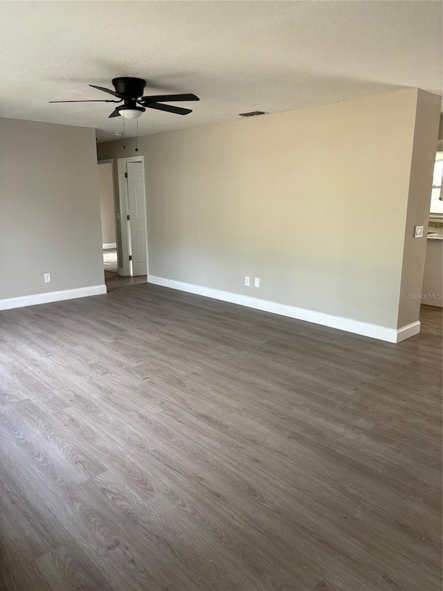 unfurnished room with a textured ceiling, dark wood finished floors, visible vents, and baseboards