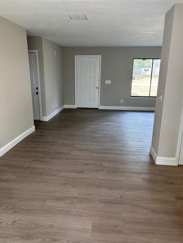 spare room with a textured ceiling, baseboards, and wood finished floors