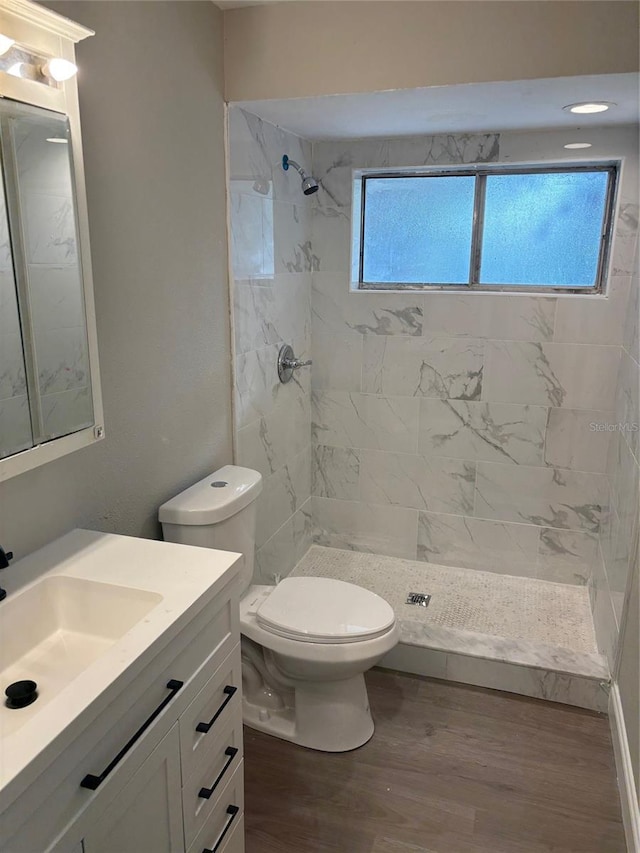 bathroom featuring toilet, a stall shower, wood finished floors, and vanity