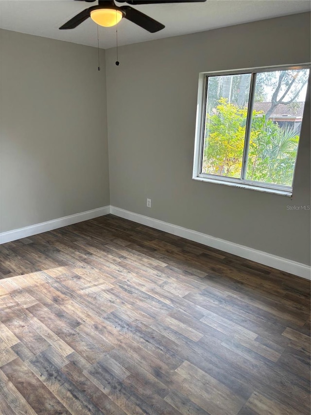 empty room featuring ceiling fan, baseboards, and dark wood-type flooring