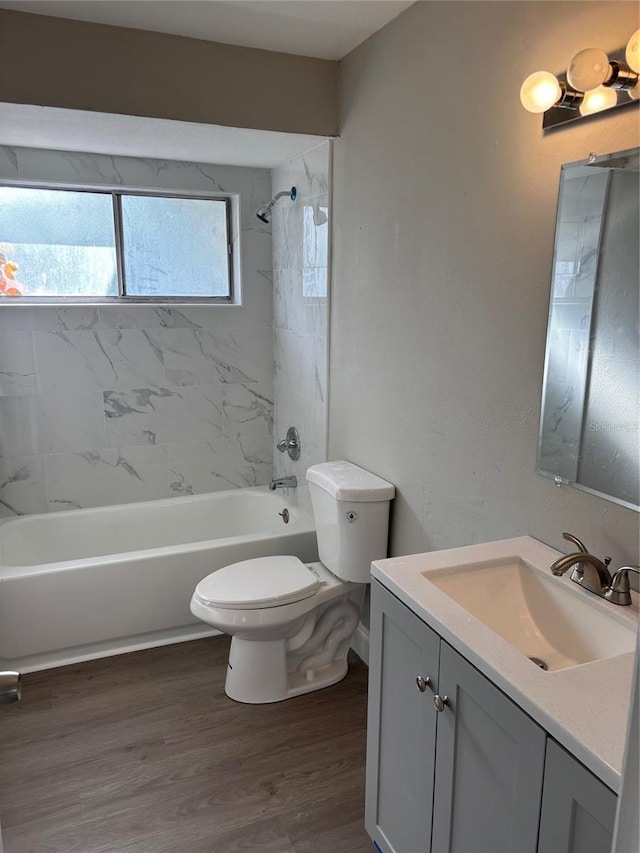 full bathroom featuring washtub / shower combination, vanity, wood finished floors, and toilet