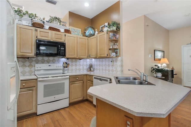 kitchen with a peninsula, white appliances, light countertops, and a sink