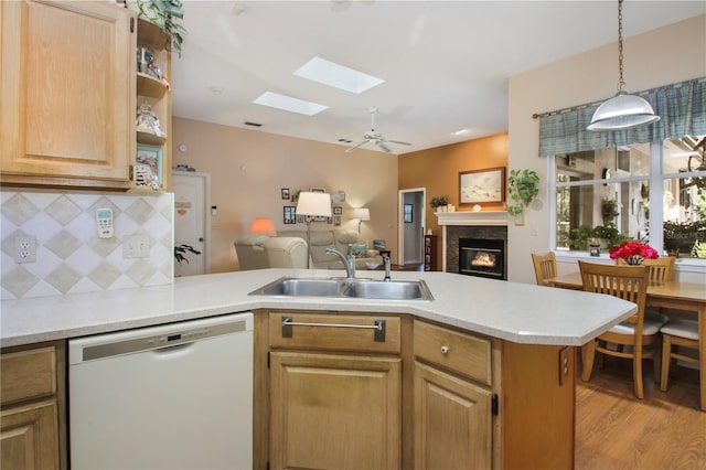 kitchen featuring a glass covered fireplace, light countertops, dishwasher, and a sink