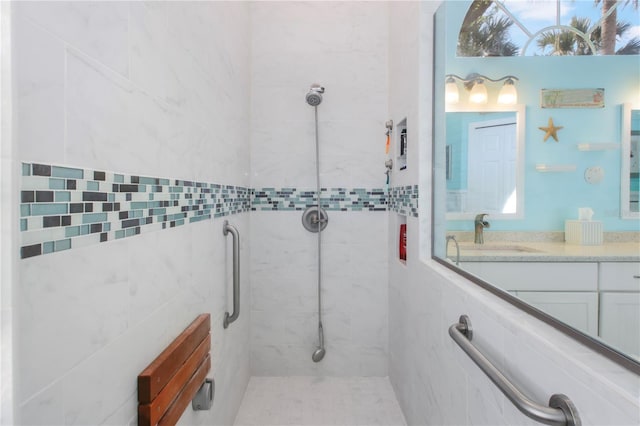 bathroom with a tile shower and vanity