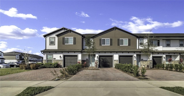 view of property with stone siding, driveway, and an attached garage