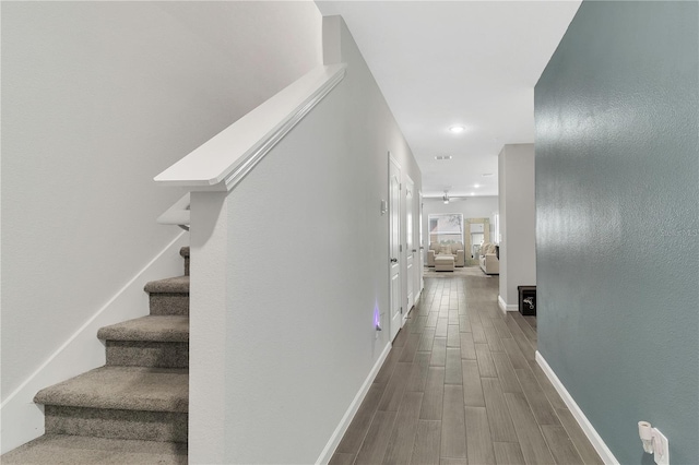 corridor featuring stairs, recessed lighting, baseboards, and wood finished floors