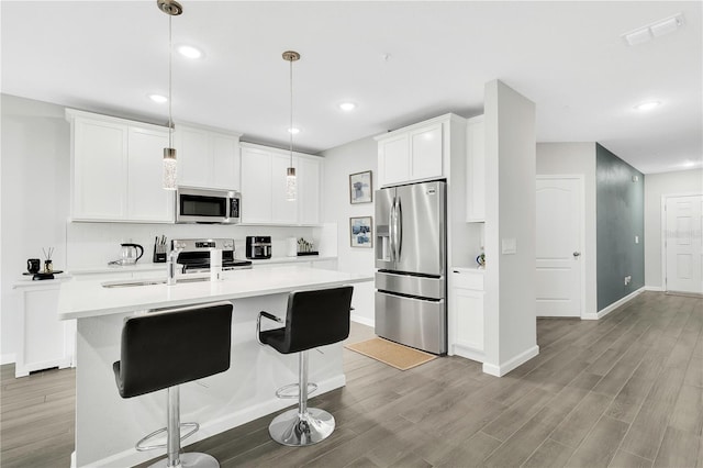 kitchen featuring stainless steel appliances, light countertops, visible vents, and wood finished floors