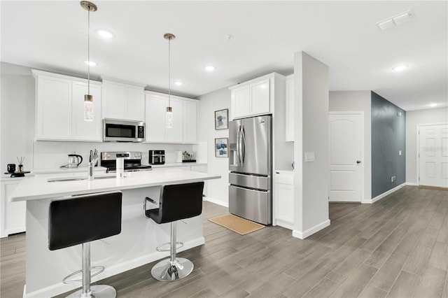 kitchen with appliances with stainless steel finishes, light countertops, light wood-type flooring, and visible vents