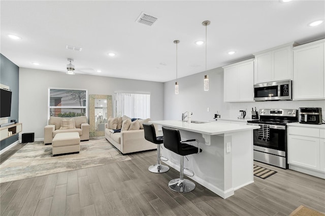 kitchen with stainless steel appliances, light countertops, visible vents, light wood-style flooring, and a sink