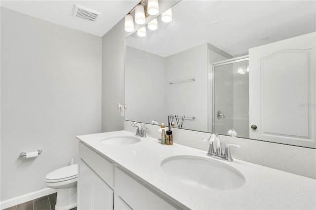 bathroom with toilet, a sink, visible vents, and a shower with door