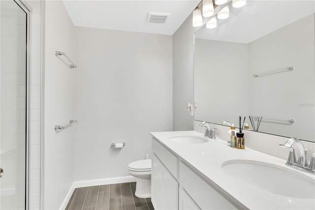 bathroom featuring toilet, wood finish floors, a sink, and visible vents