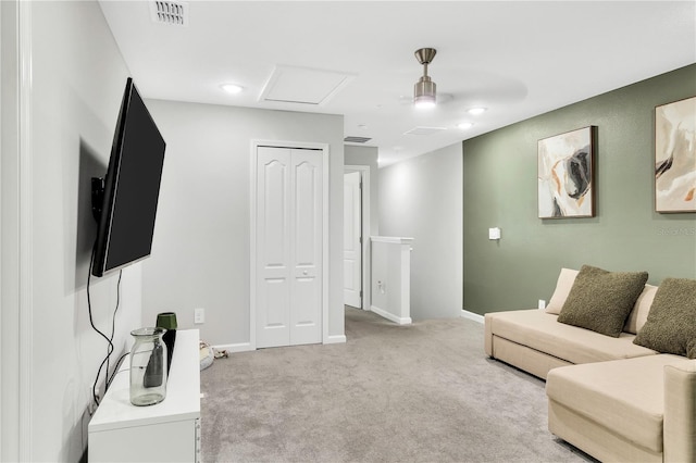 living room featuring attic access, visible vents, baseboards, and light colored carpet