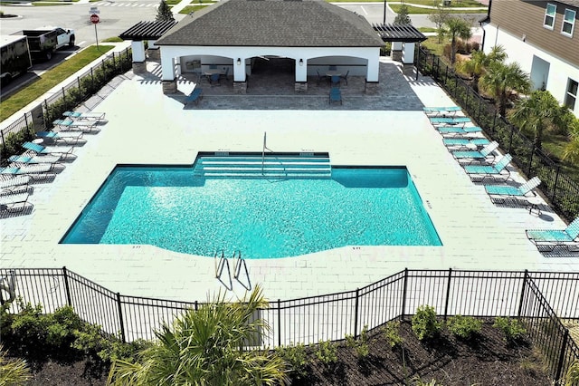 pool with a patio area and fence