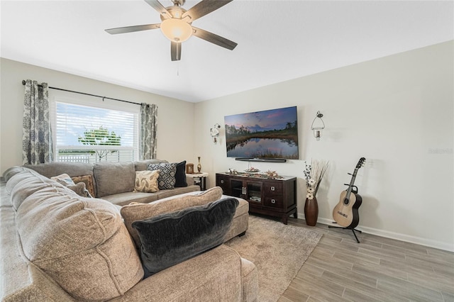 living area with light wood-style flooring, baseboards, and a ceiling fan