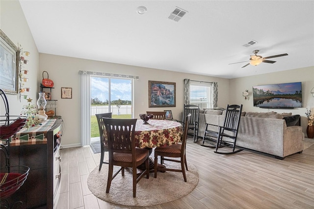 dining space featuring a ceiling fan, baseboards, visible vents, and light wood finished floors