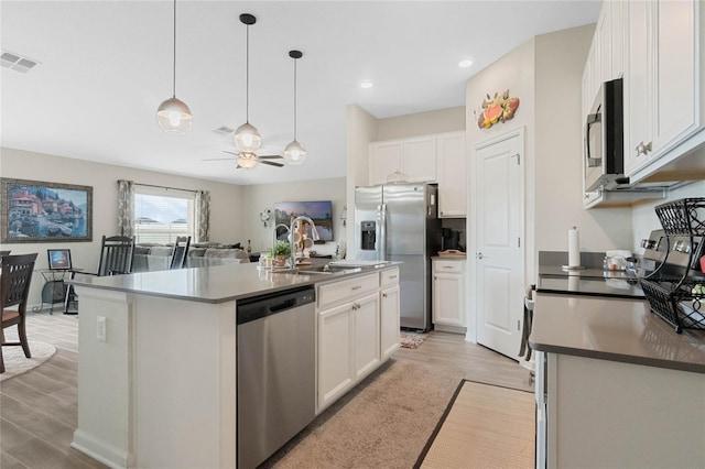 kitchen featuring visible vents, white cabinets, appliances with stainless steel finishes, light wood finished floors, and dark countertops