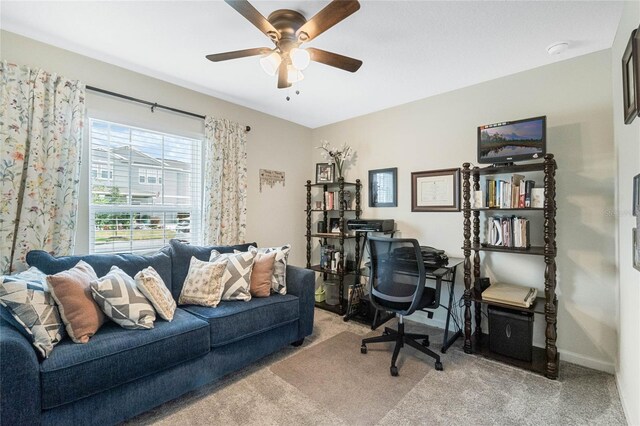 office area featuring light carpet, a ceiling fan, and baseboards