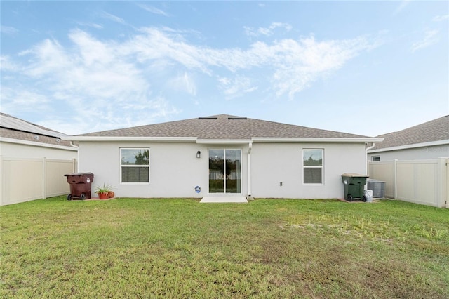 back of house featuring fence private yard, a lawn, and stucco siding