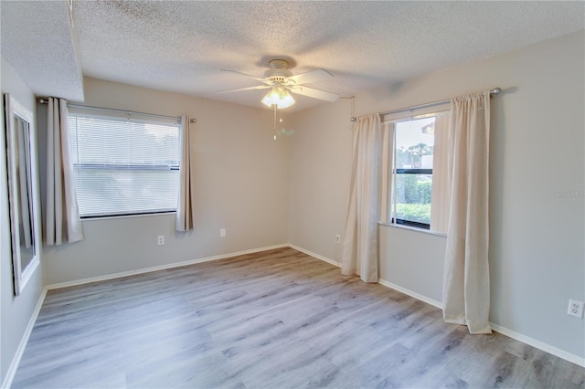 spare room with a textured ceiling, baseboards, and wood finished floors