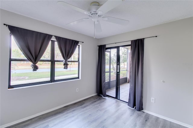 empty room featuring wood finished floors, a ceiling fan, and baseboards