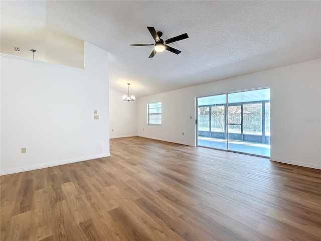 unfurnished room featuring visible vents, baseboards, wood finished floors, a textured ceiling, and ceiling fan with notable chandelier