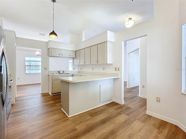 kitchen featuring light countertops, visible vents, light wood-style floors, a sink, and a peninsula