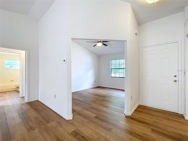 entrance foyer featuring high vaulted ceiling, wood finished floors, a ceiling fan, and baseboards