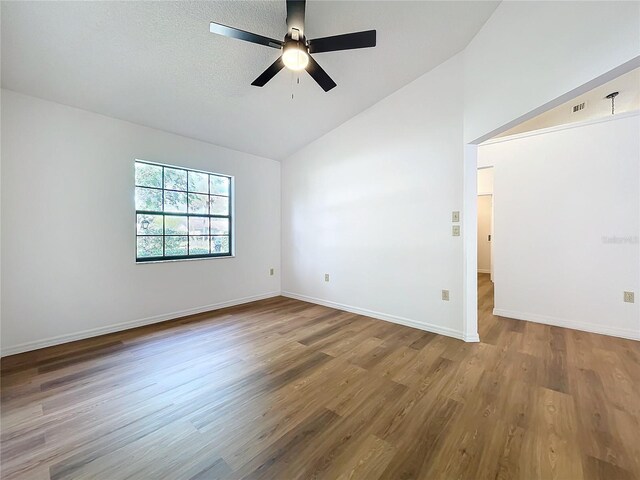 unfurnished room with baseboards, a ceiling fan, lofted ceiling, wood finished floors, and a textured ceiling