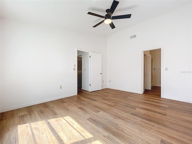 unfurnished bedroom featuring visible vents, light wood-style flooring, baseboards, and a textured ceiling