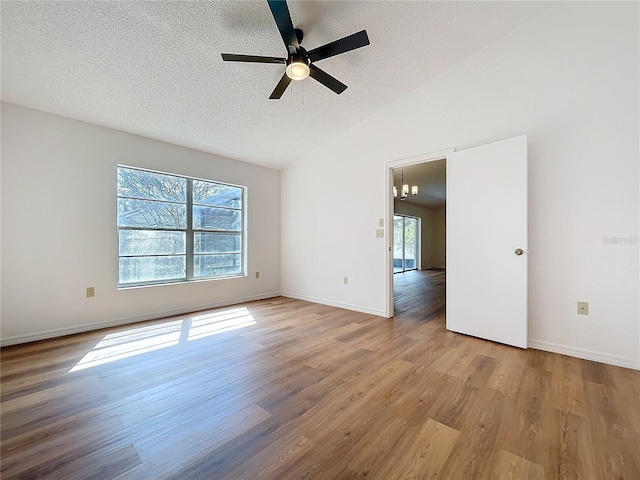 spare room with baseboards, a ceiling fan, lofted ceiling, wood finished floors, and a textured ceiling