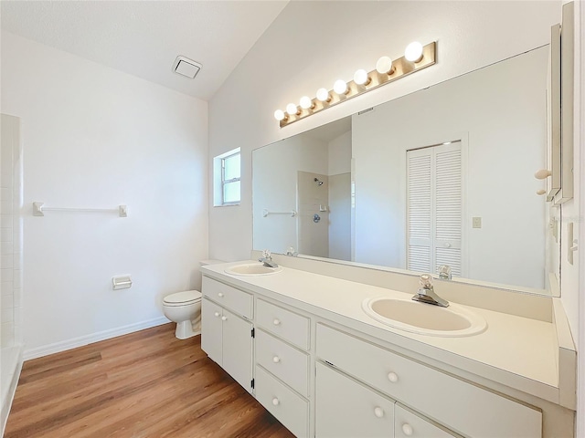 bathroom featuring wood finished floors, a sink, toilet, and walk in shower