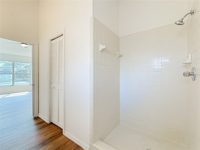 bathroom featuring a closet, baseboards, a tile shower, and wood finished floors